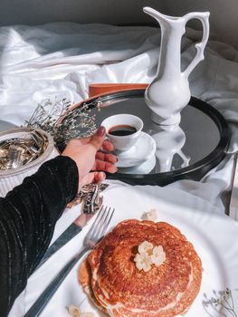 A stylish breakfast scene with pancakes, coffee, and a graceful hand adding charm.