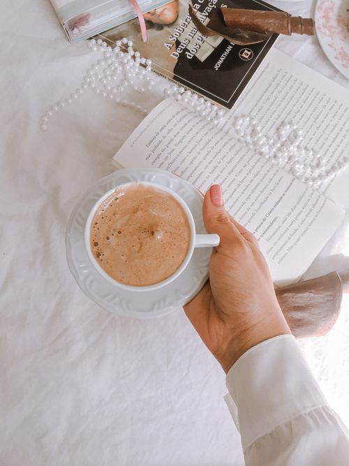 Free Top view of a coffee cup held over an open book with pearls and a relaxing atmosphere. Stock Photo