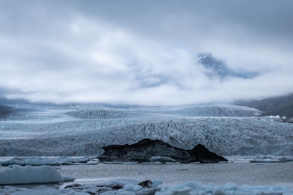 A breathtaking view of a frozen glacier surrounded by icy sea under an overcast sky.