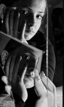 A black and white portrait capturing a woman's reflection in a broken mirror, symbolizing introspection.