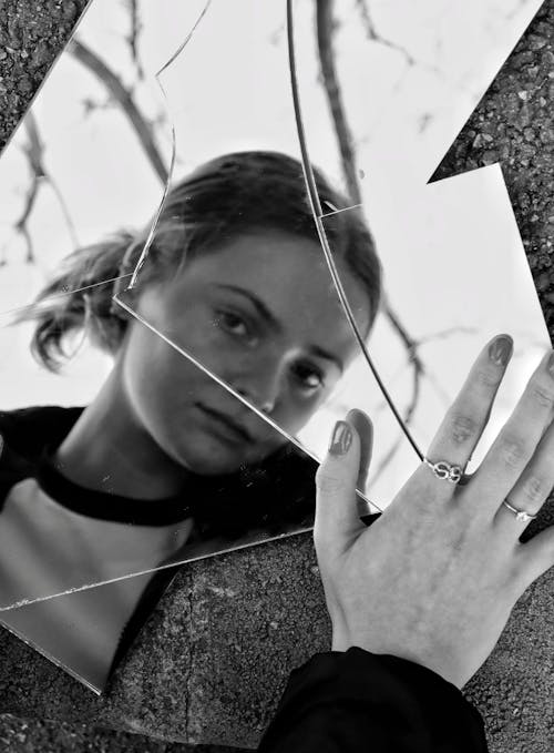 Free Woman Looking into a Broken Mirror on the Ground  Stock Photo