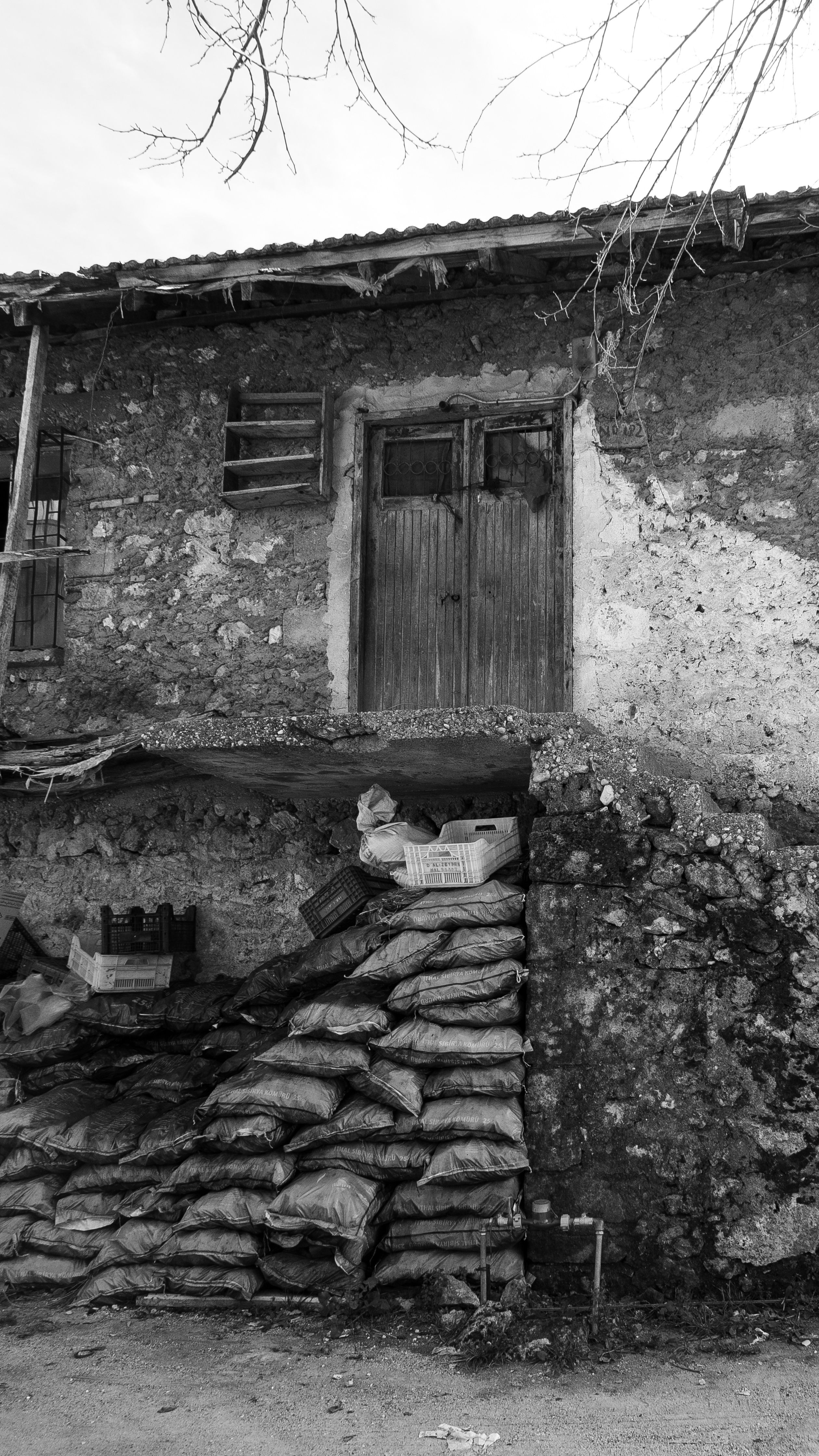 A vintage black and white photo of an abandoned stone house with a rustic facade.