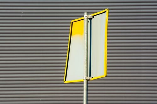 Free Close-up of a sunlit urban road sign against a textured gray background, outdoors. Stock Photo