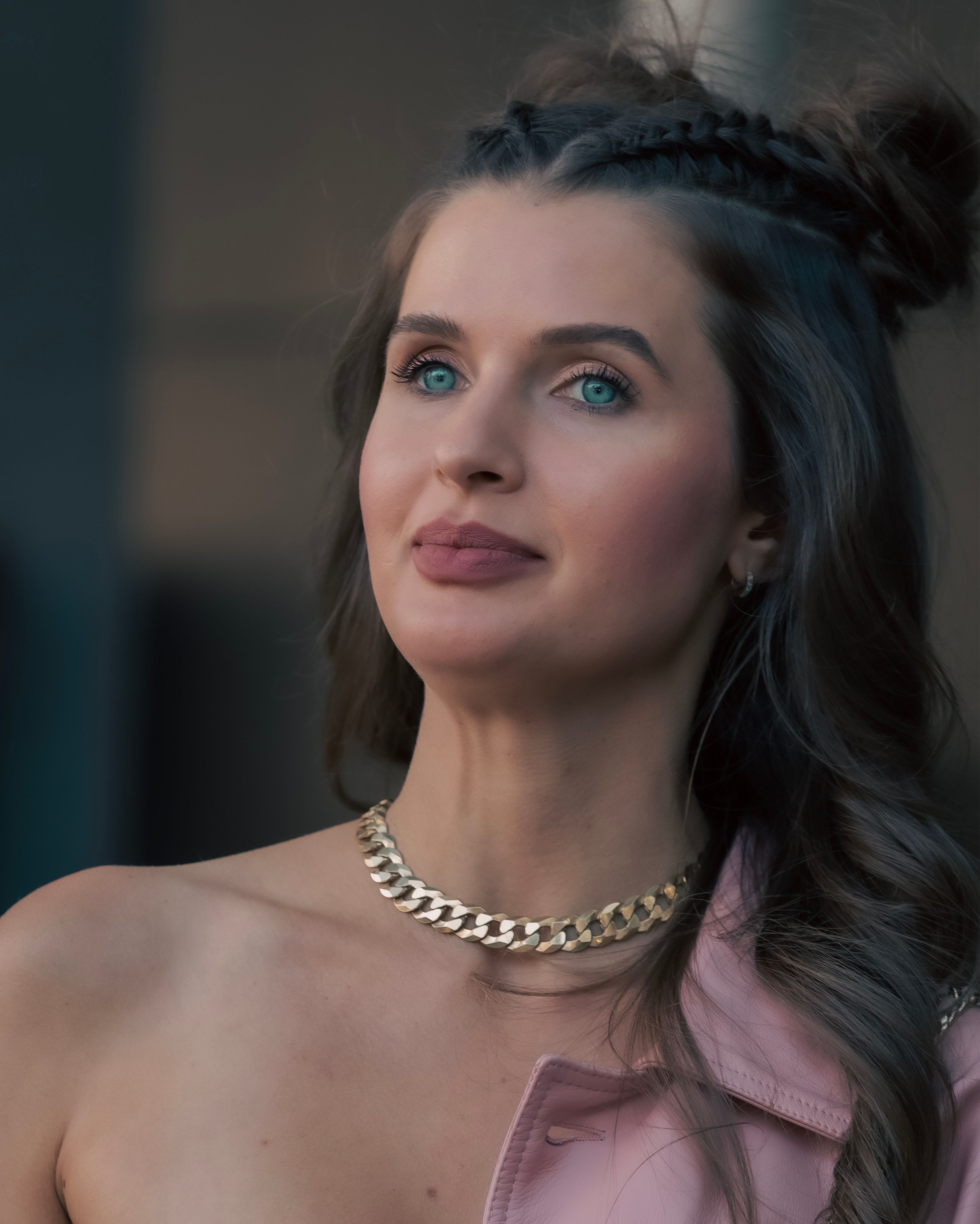 Portrait of an elegant woman with braided hair and gold jewelry posing outdoors in New York City.