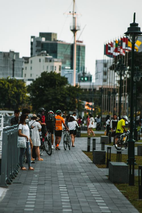 Free A lively day in Hồ Chí Minh City park with people walking and cycling, surrounded by greenery and modern buildings. Stock Photo