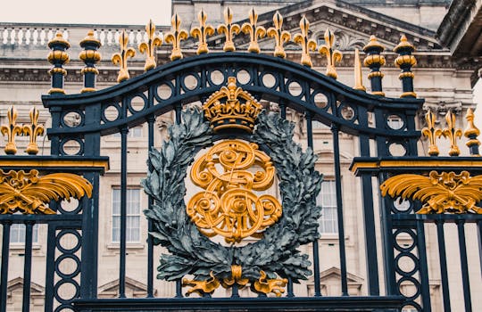 Detailed view of the ornate gold and black iron gate at Buckingham Palace, London. by Roméo