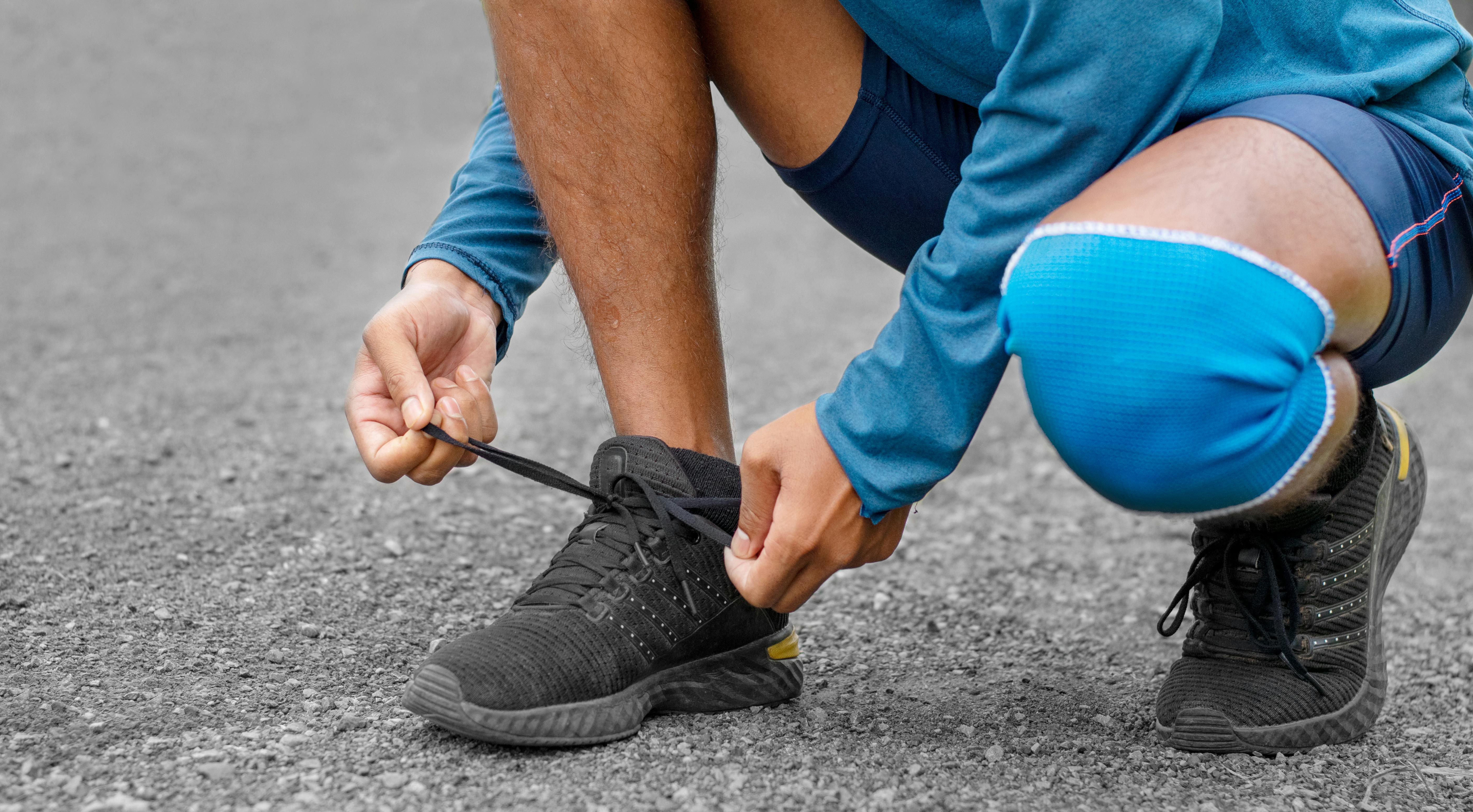 a man tying his shoe with a blue knee brace