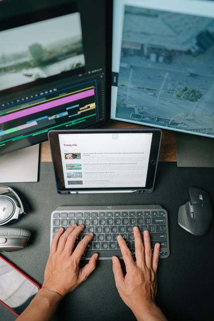 Person typing on keyboard in modern workspace with multiple screens displaying content. - How to repurpose Old Blog Articles into Social Media Posts Efficiently