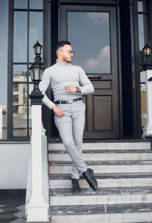 Free Stylish man in modern outfit leaning on steps by a doorway, exuding confidence. Stock Photo