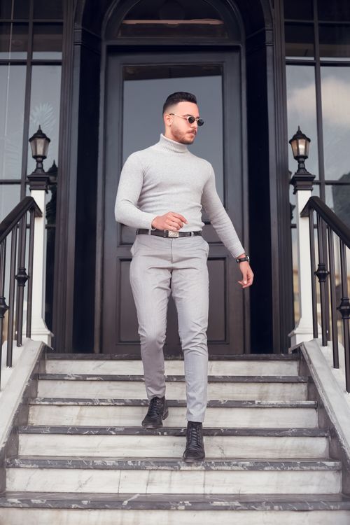 Free Stylish man in grey outfit walking down steps outdoors, exuding confidence. Stock Photo