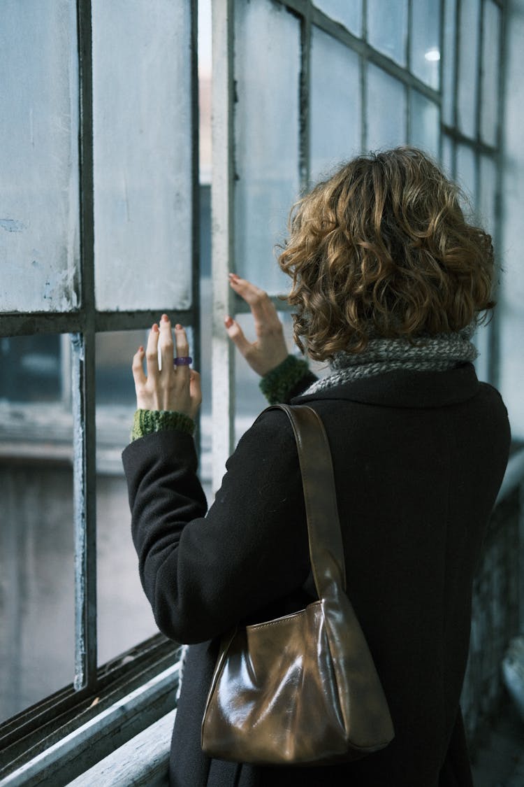 Back View Of A Woman Touching The Window Glass