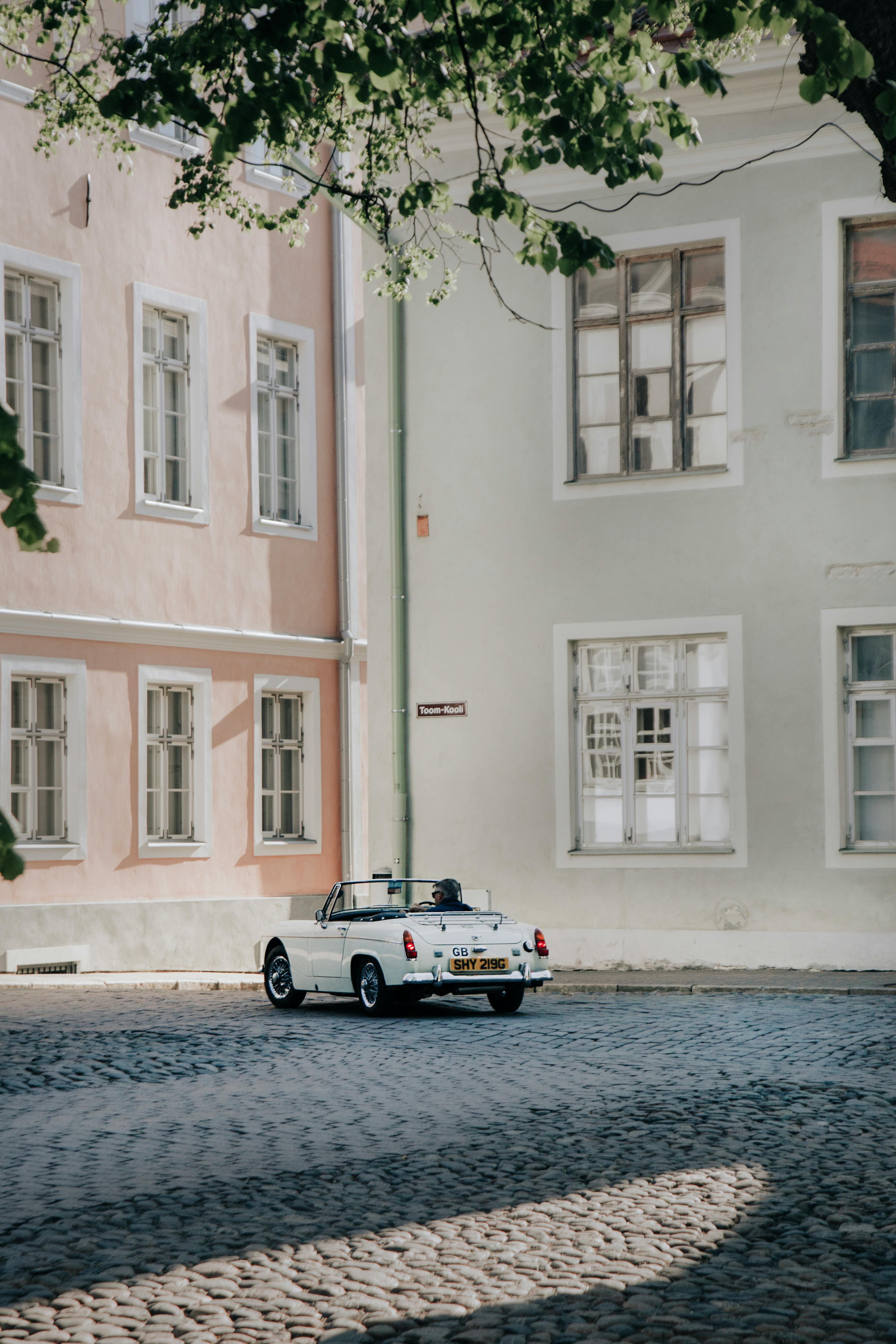 A classic white convertible parked on a sunny cobblestone street in Tallinn, Estonia.