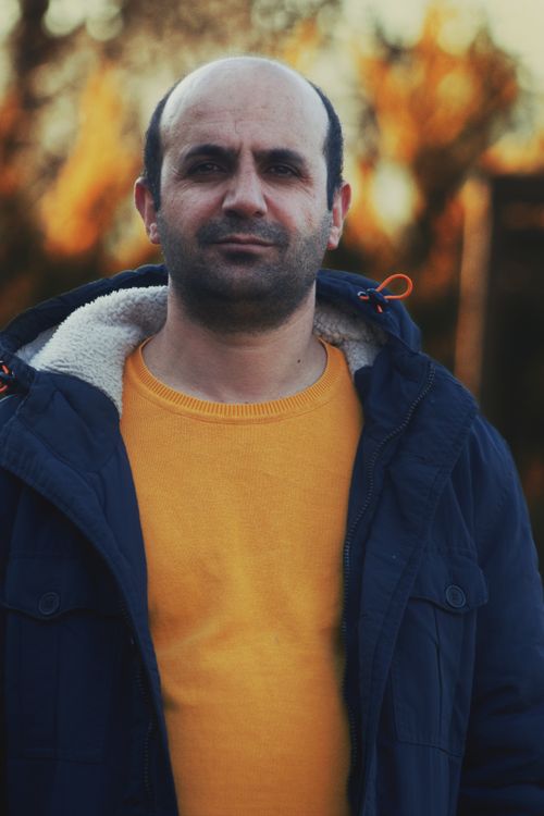 Free Casual portrait of a balding man in a yellow sweatshirt and jacket, photographed outdoors during day. Stock Photo
