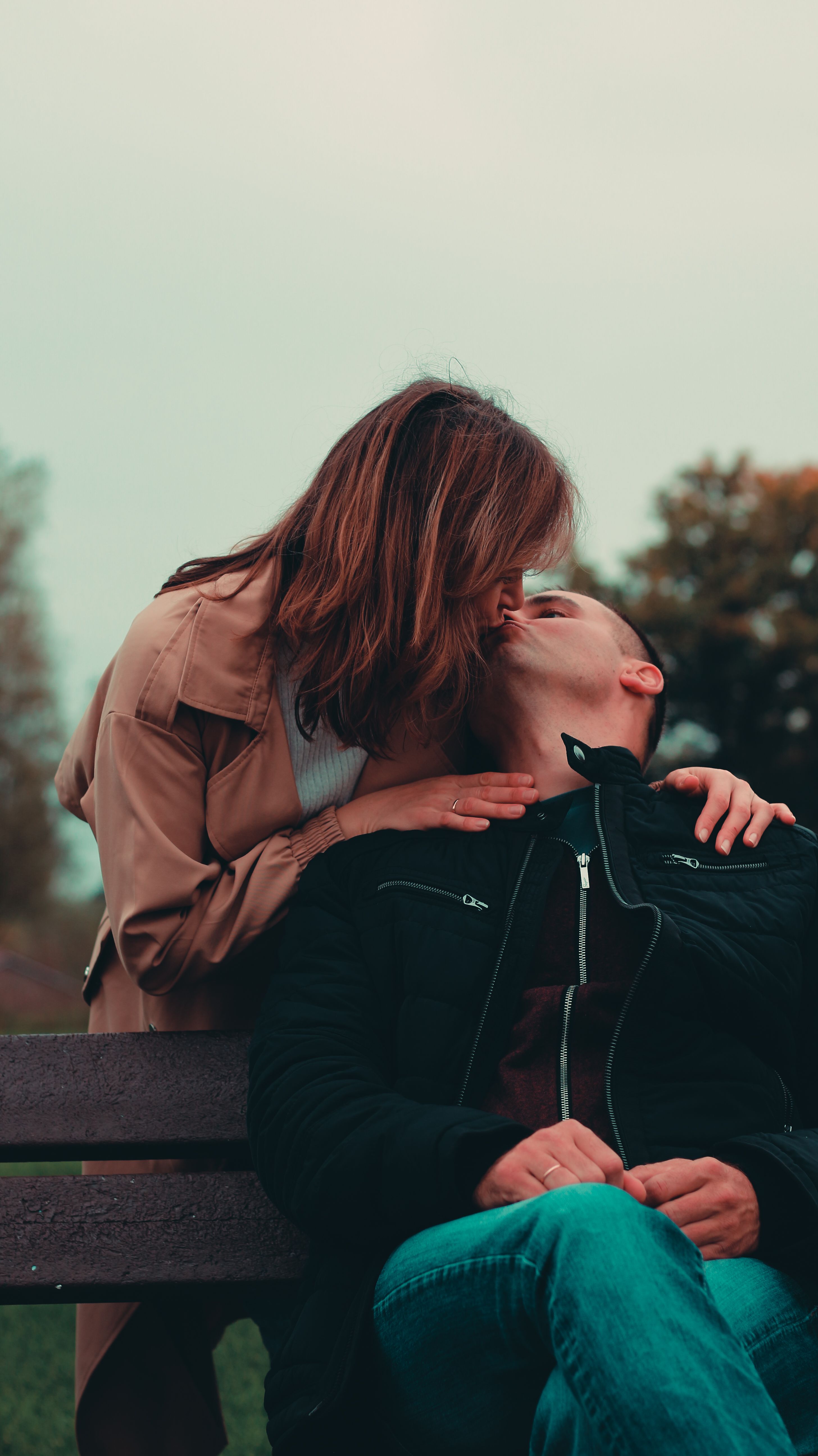 A couple sharing a tender kiss outdoors, embodying love and connection.
