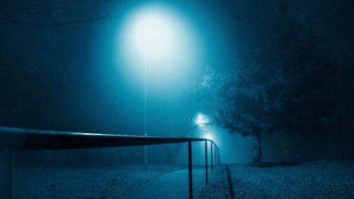 Free Eerie night scene in a foggy park with illuminated streetlamps and trees. Stock Photo