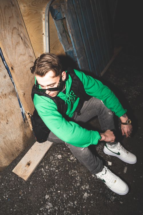 Free Young man in casual urban attire sitting in a gritty alley at night, Gatineau, Canada. Stock Photo