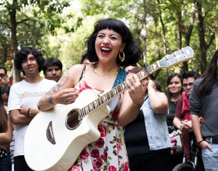 Woman playing guitar with a lively crowd in a vibrant street setting.