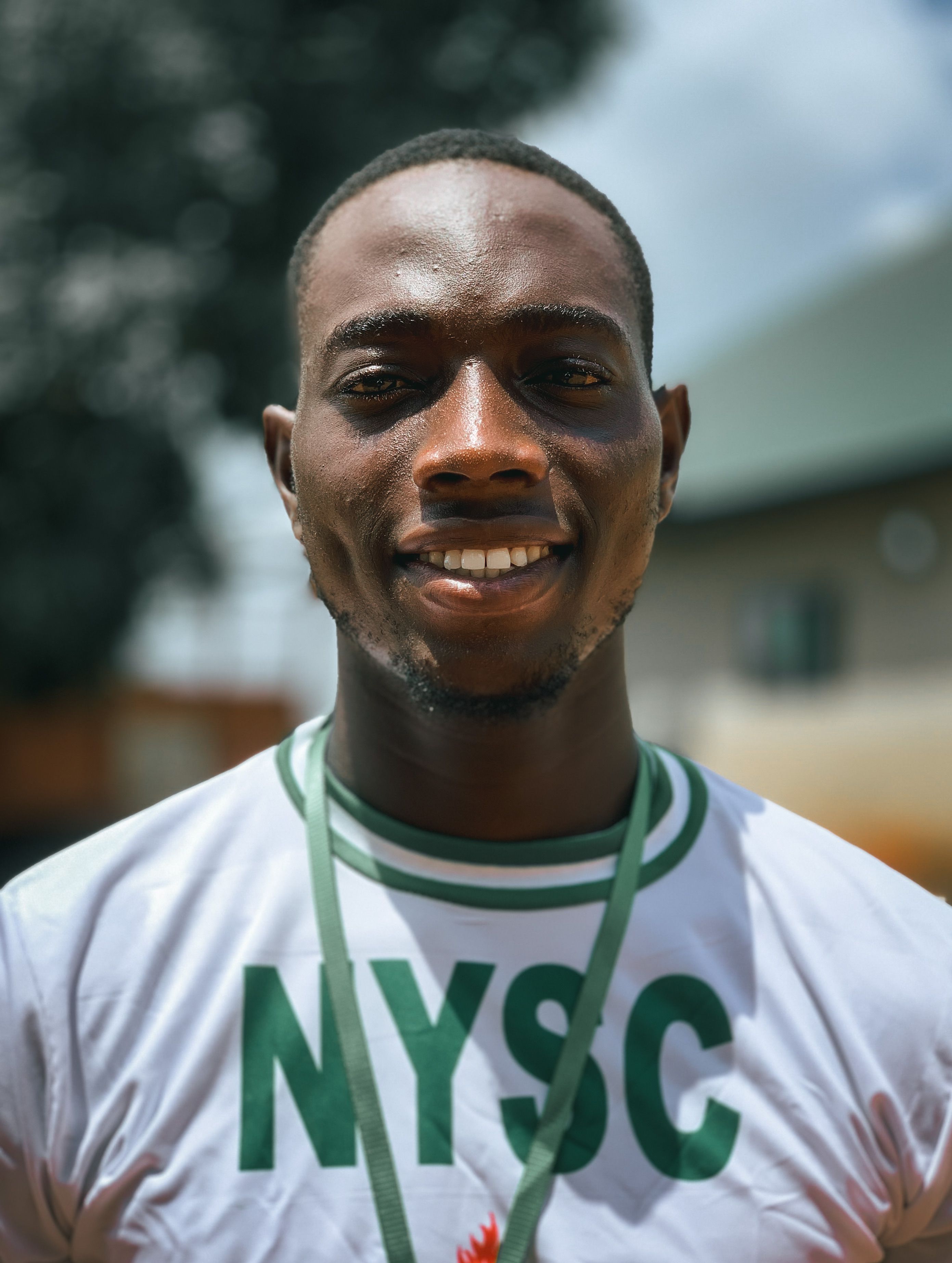 Portrait of a young African man smiling outdoors in sportswear, showcasing joy and positivity.