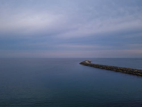 View of a Long Pier on a Calm Sea under a Cloudy Sky 