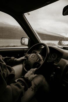Close-up of hands on a Honda steering wheel during a rainy drive with scenic view outside.