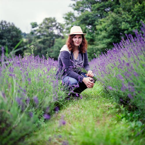 Woman Wearing Purple Jacket in Brown Hat during Day Time