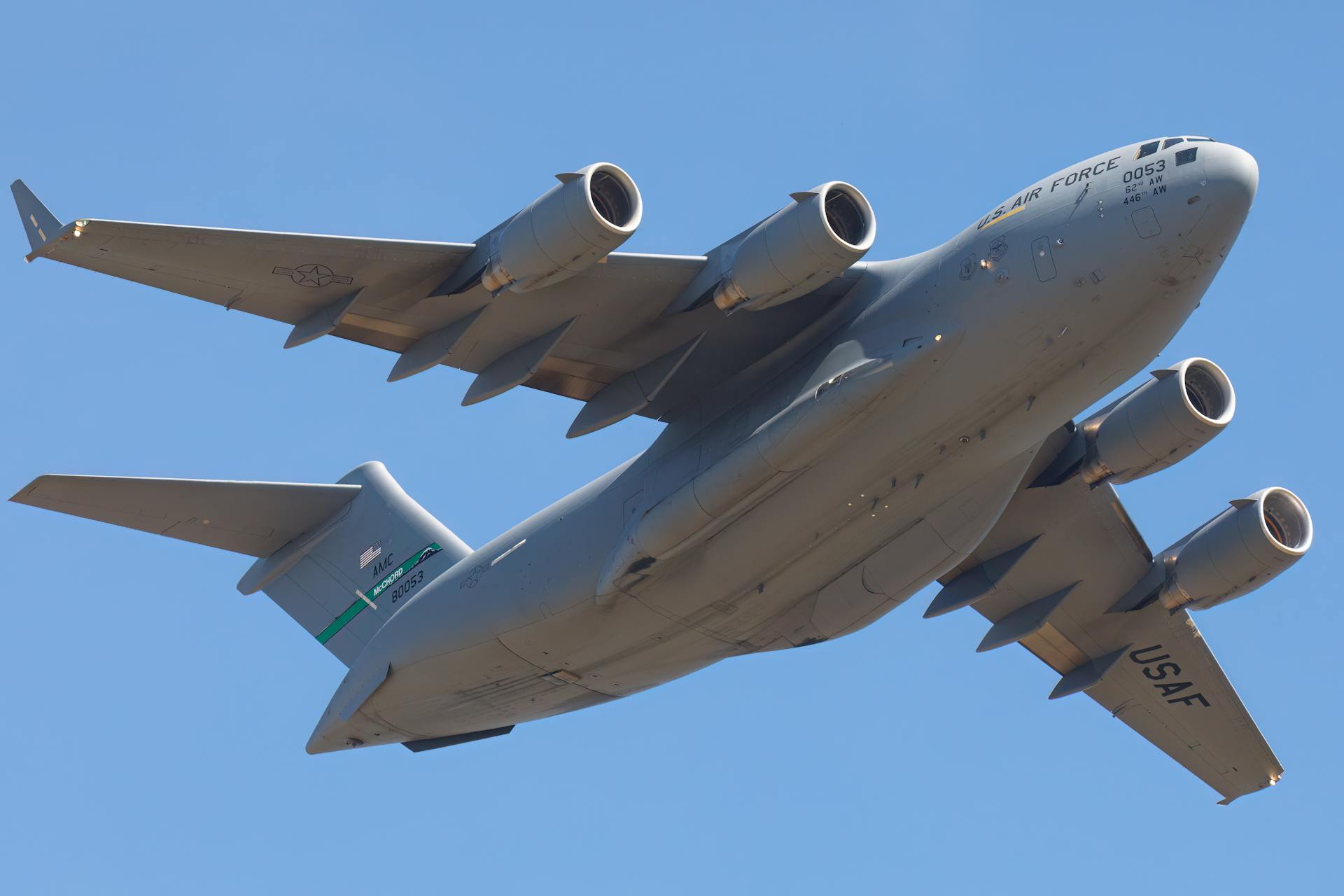 A C-17 military aircraft soaring majestically against a clear blue sky, showcasing its powerful design.