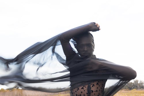 A woman in a black dress is holding a black veil