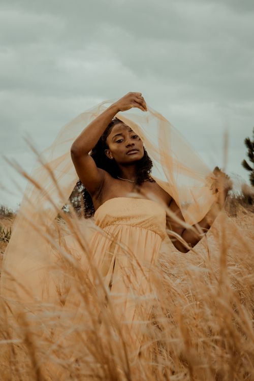A woman in a yellow dress is standing in tall grass · Free Stock Photo