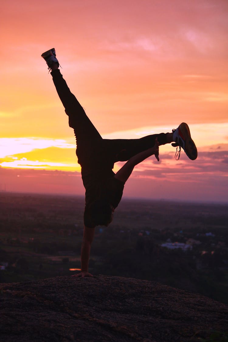 Person Doing Handstand On Hilltop At Sunset