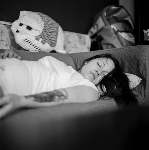 Woman in White Shirt Sleeping on Gray Fabric Sofa