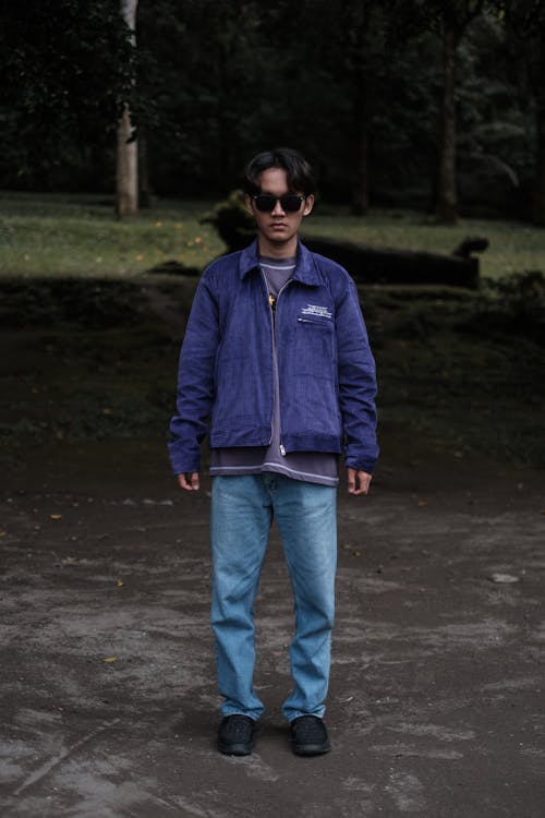 Young Man in Blue Jacet and Jeans Posing in a Park 