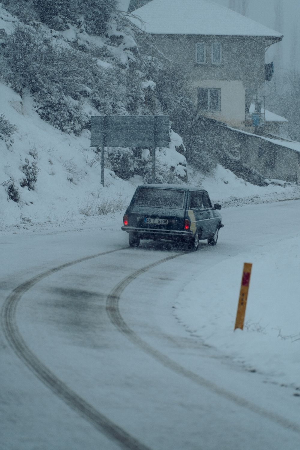 Car driving on a snow-covered road during snowfall