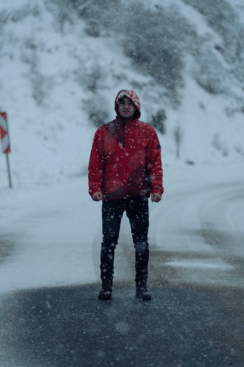 Man Wearing Red Coat Standing on Road in Snowstorm
