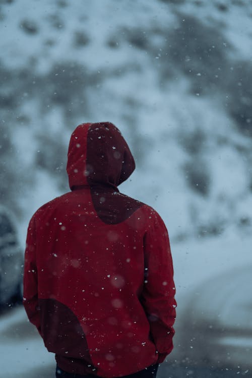 Person in Red Coat Standing on Road in Snowstorm