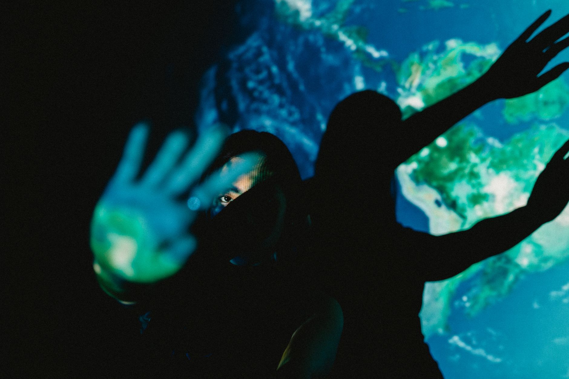 Creative silhouette of hands against Earth projection, exploring shadows and light.