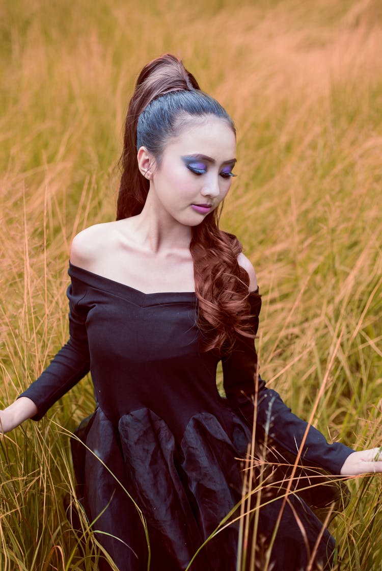 Woman In Dress Posing Among Grasses