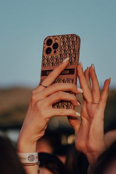 Close-up of hands capturing a concert moment on smartphone with stylish phone cover.