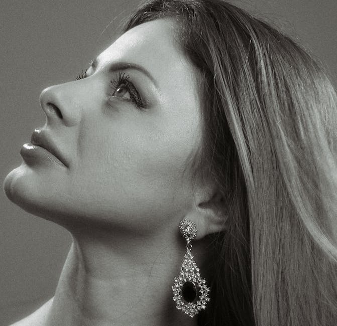 Elegant black and white headshot of a woman with long hair looking upwards.