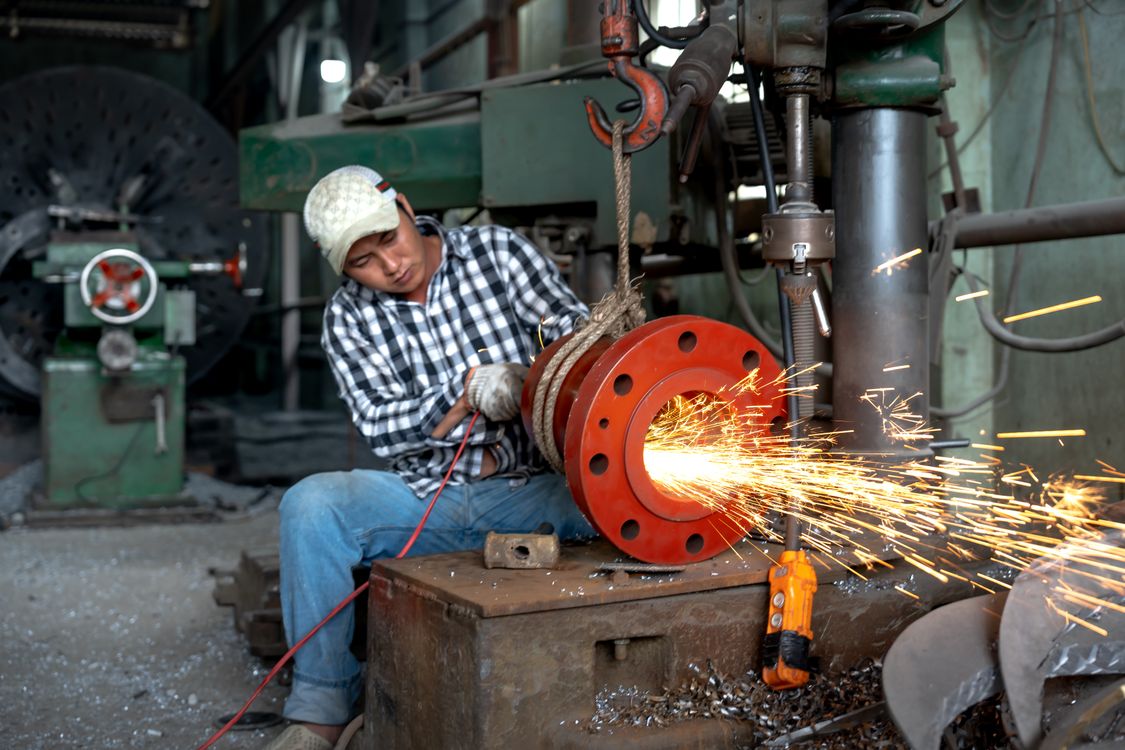 Man Using a Grinder in a Warehouse ยท Free Stock Photo