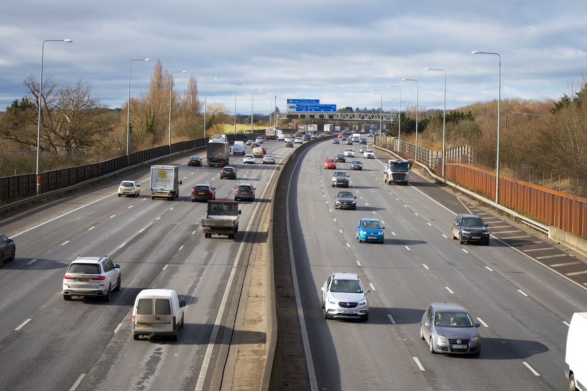 Aerial view of a UK motorway with several lanes of traffic and overhead route signs