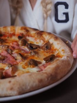 Close-up of a savory mushroom and ham pizza served in an Italian pizzeria.