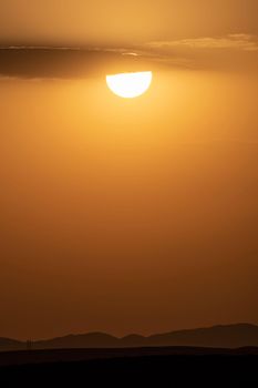 Mesmerizing sunset over rolling hills in Mashhad, Iran with a golden sky and sun silhouette.