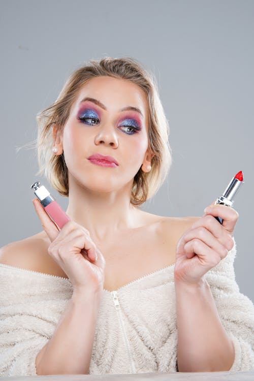 A woman with makeup on her face holding a lipstick