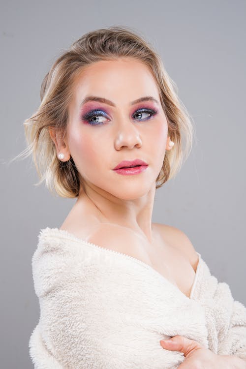 A woman with pink makeup and a white sweater