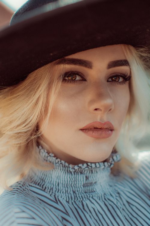 Free Close-up portrait of a stylish blonde woman with a black hat, showcasing elegant fashion and beauty. Stock Photo