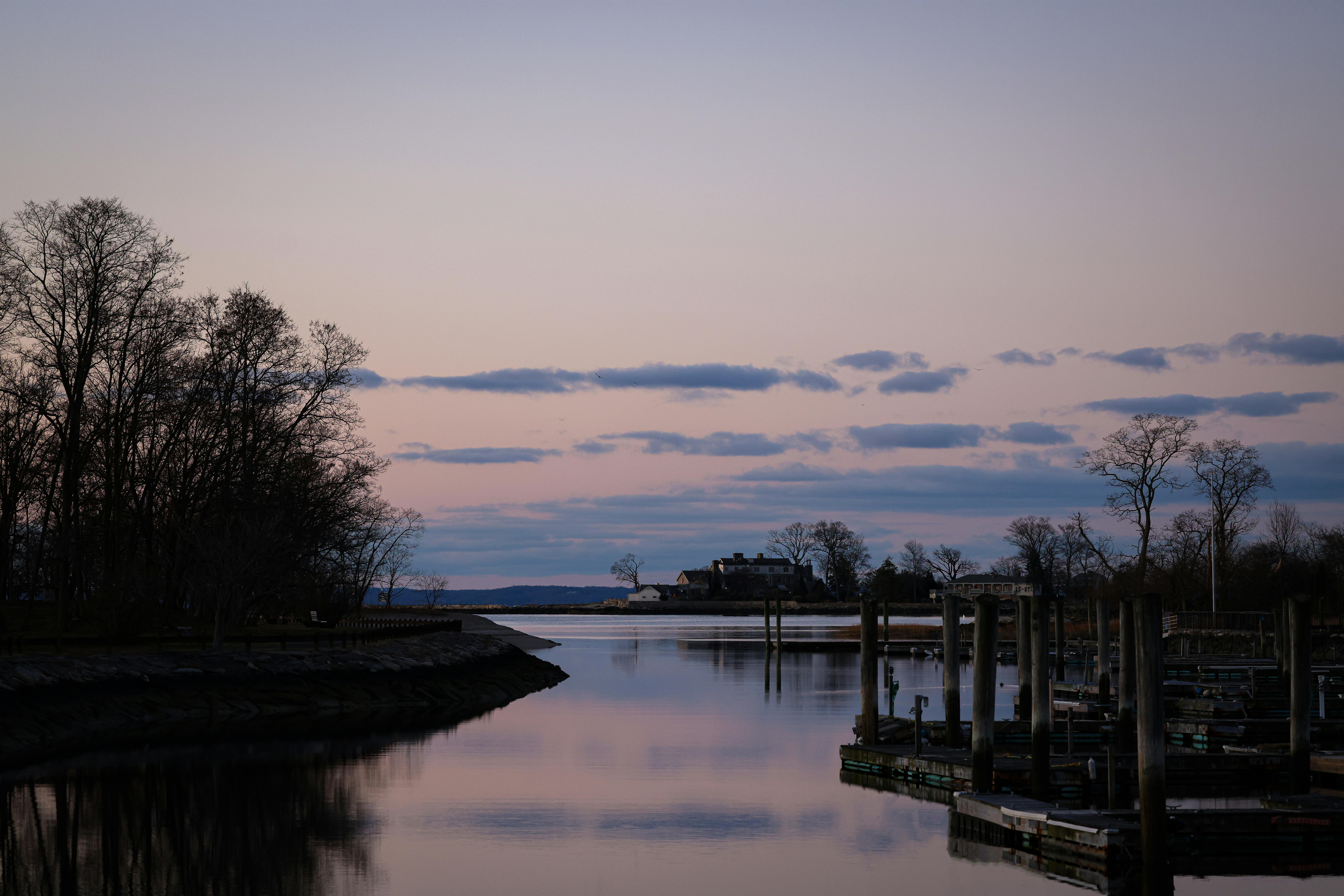 A serene dusk view of the waterfront in Stamford, CT, with calm waters and silhouetted trees.