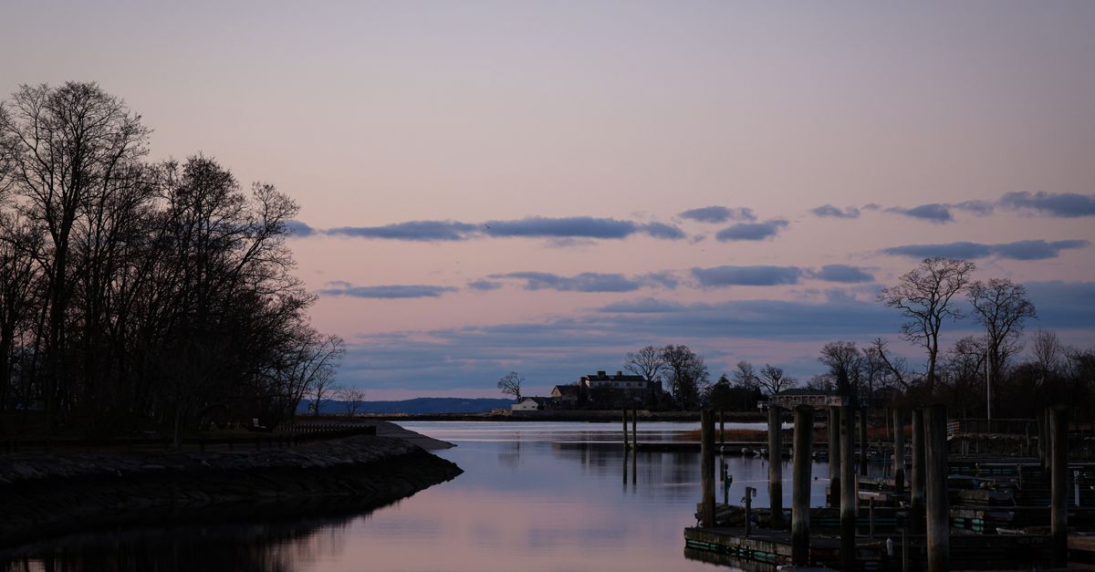 A serene dusk view of the waterfront in Stamford, CT, with calm waters and silhouetted trees.