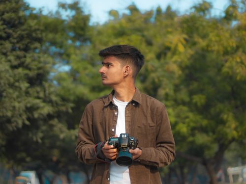 Free Young man holding a camera, exploring natural surroundings with focus on expression and exploration. Stock Photo