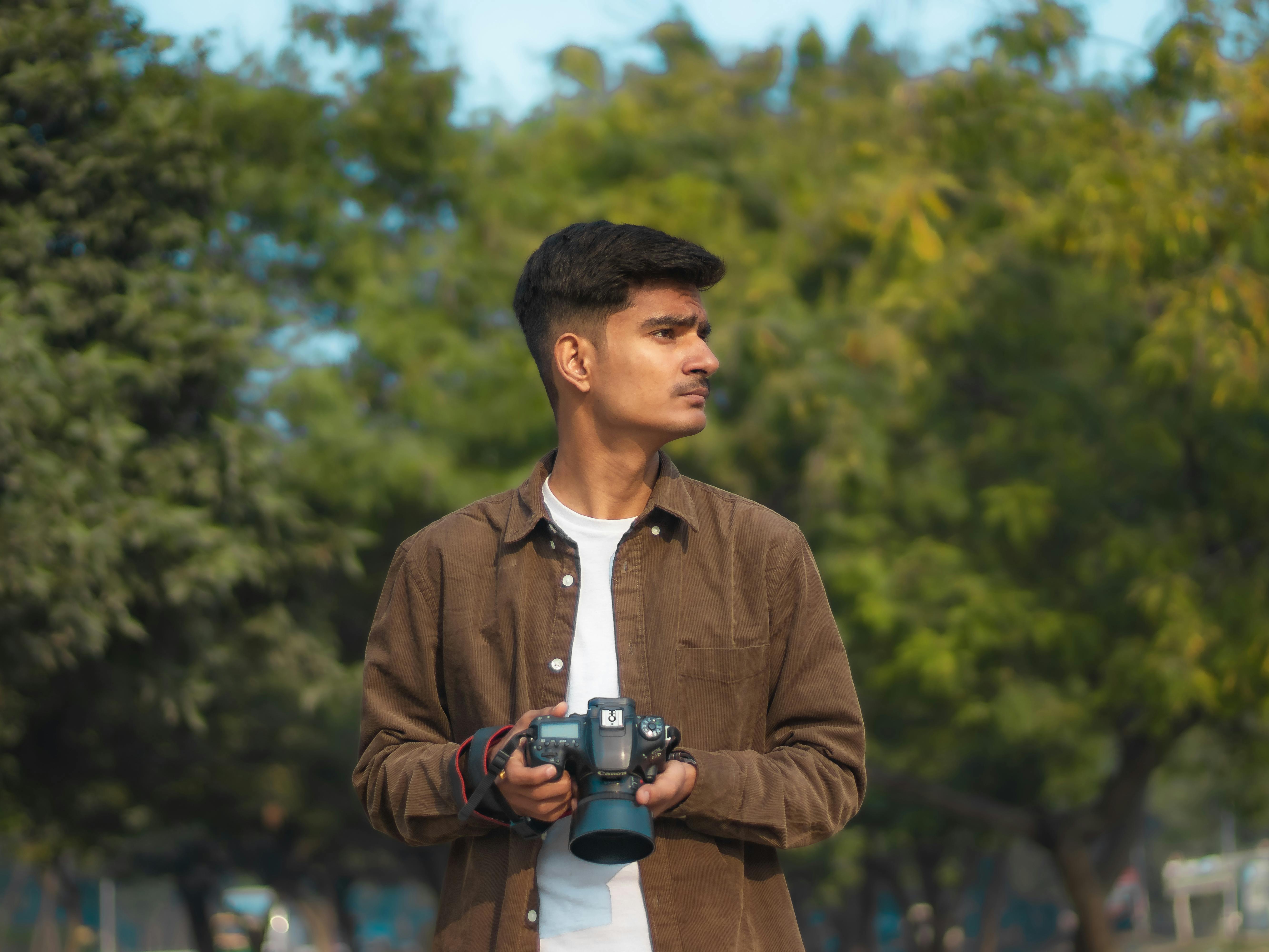 Young man focusing with photo camera and looking at camera · Free Stock  Photo