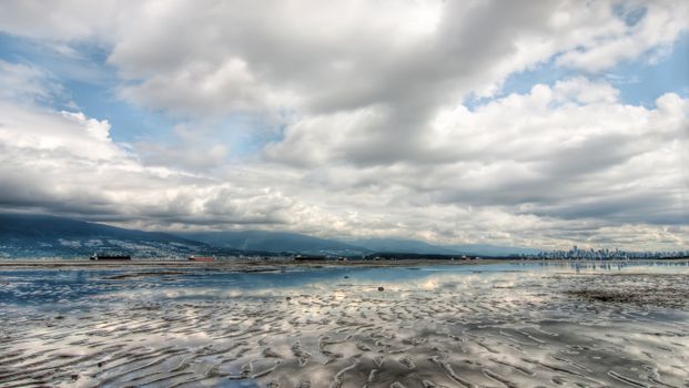 Panoramic view of Vancouver coast with cloudy sky reflecting on calm sea waters.